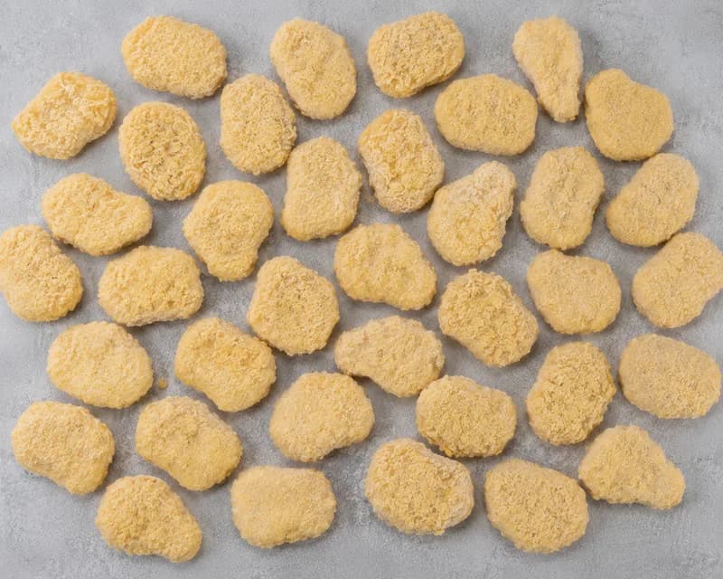 Uncooked breaded chicken nuggets spread in a single layer